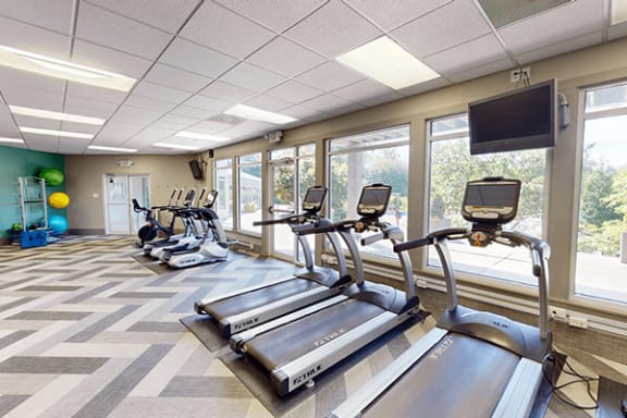 a gym with cardio machines and a tv