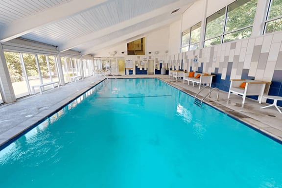 a large indoor swimming pool with blue water and chairs