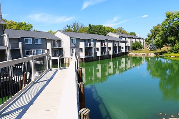 a boardwalk over a body of water in front of a row of apartment buildings