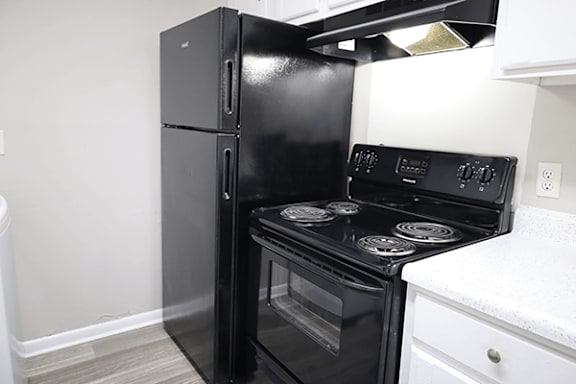 A black refrigerator and stove in a kitchen.