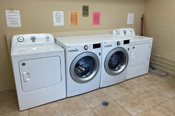 a row of washing machines and dryers in a laundry room