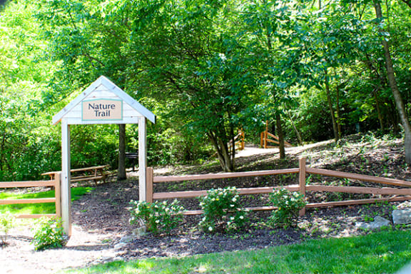 the entrance to the nature trail with a wooden fence and a sign