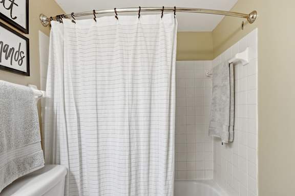 A white shower curtain hanging in a bathroom.