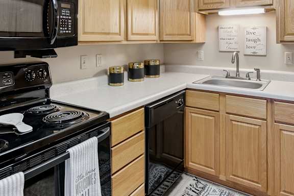 A kitchen with a black stove top oven and wooden cabinets.