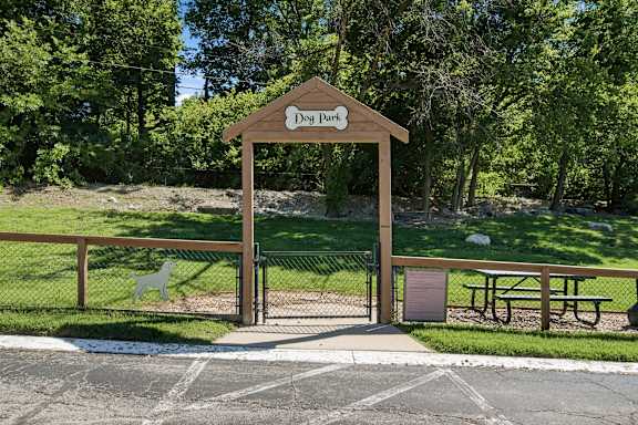A wooden sign that says Dog Park is on top of a gate.