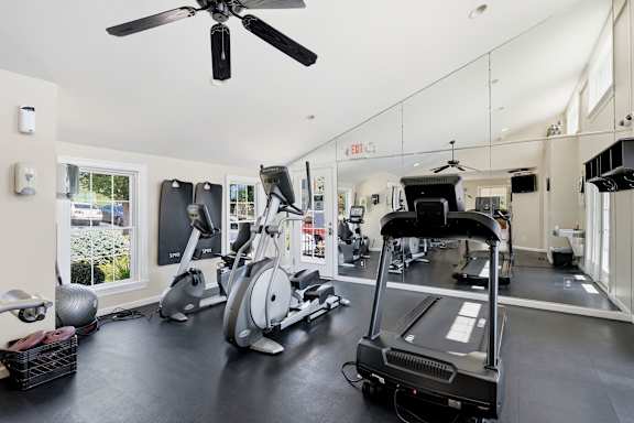 A gym with a treadmill, elliptical trainer, and other exercise equipment.