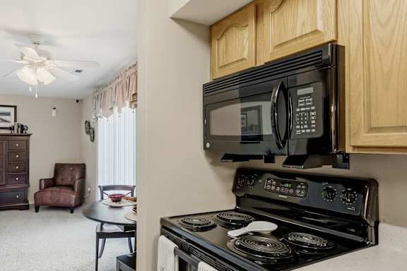 A black microwave is mounted above a black stove in a kitchen.