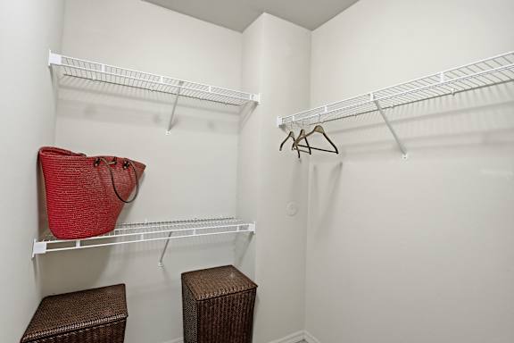 A white closet with a red bag hanging on the left side and a brown bag hanging on the right side.