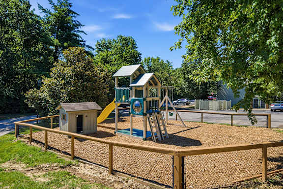 A playground with a wooden fence and a yellow slide.