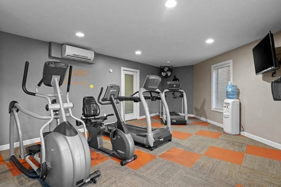 a gym with several exercise machines and a tv