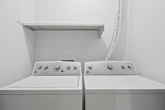 two white washing machines in a white laundry room