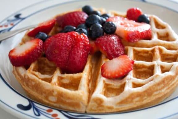 a waffle with strawberries and blueberries on a plate