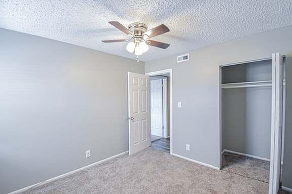 an empty room with a ceiling fan and a door to a closet