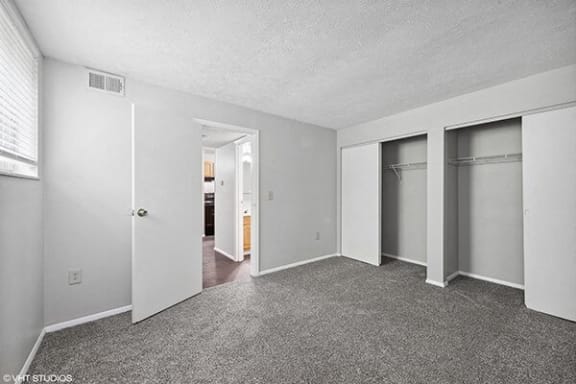 an empty bedroom with closet doors and a carpeted floor