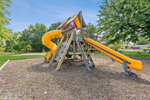a swing set with a yellow slide in a park