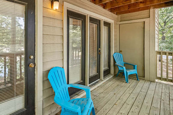 two blue rocking chairs on a porch with windows