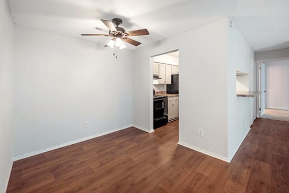 A room with a ceiling fan and wooden floors.