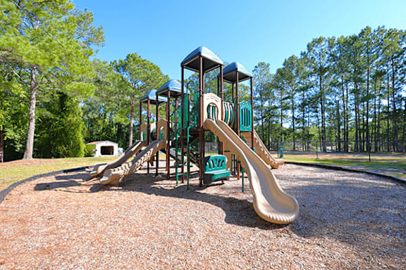 A playground with a green slide and a brown play structure.