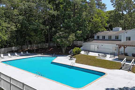 A large swimming pool surrounded by trees and a house.