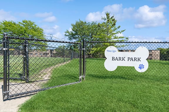 a park with a fence and a sign in the grass