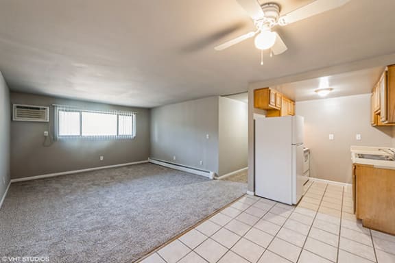 an empty living room with a white refrigerator