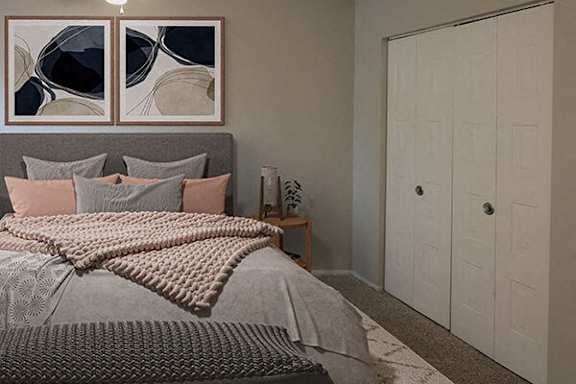 A bedroom with a bed, pillows, a blanket, and a painting on the wall.