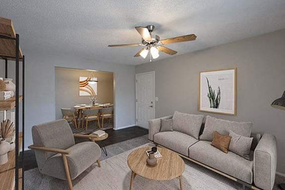 A living room with a grey couch, a wooden chair, and a ceiling fan.
