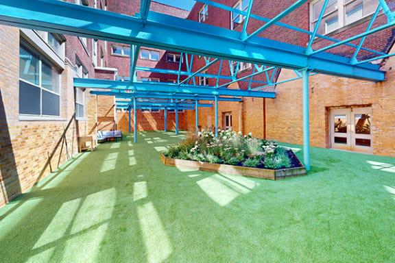a patio with green grass and a flower bed in front of a brick building