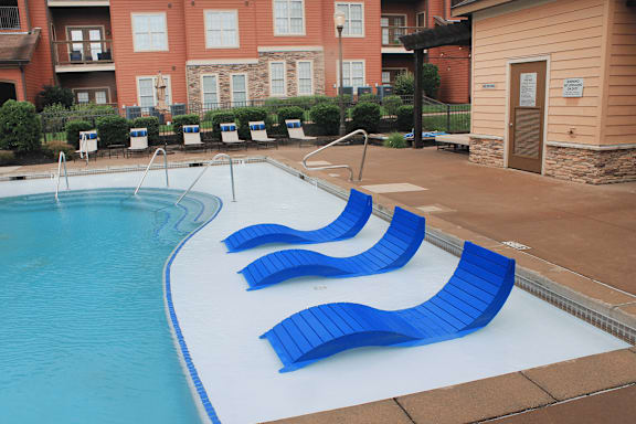 A pool with blue chairs and a building in the background.