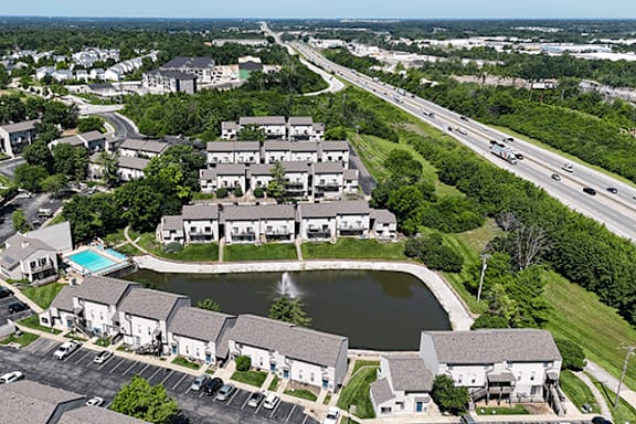 A bird's eye view of a residential complex with a swimming pool and a road passing by.