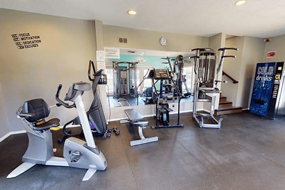A gym with a variety of equipment including treadmills, weights, and exercise machines.