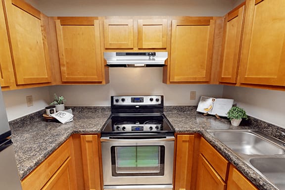 A kitchen with wooden cabinets and a stove top oven.