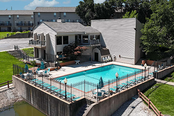 A small pool with a deck and a building in the background.