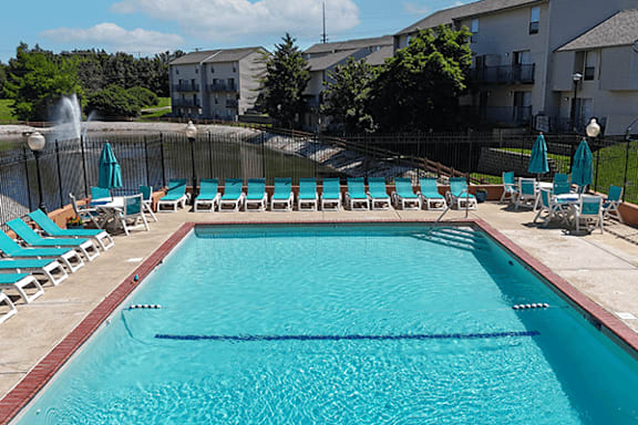 A large swimming pool with blue water and lounge chairs.