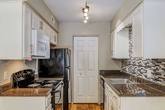 A kitchen with black appliances and white cabinets.