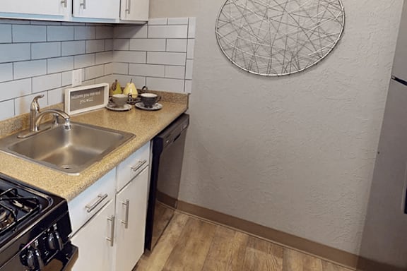 A kitchen with a sink, stove, and a wall hanging.