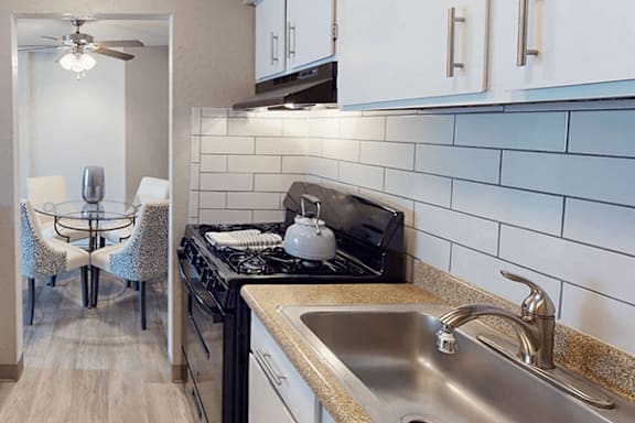 A kitchen with a black stove top oven and a silver sink.