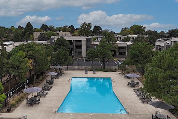A large swimming pool surrounded by trees and chairs.