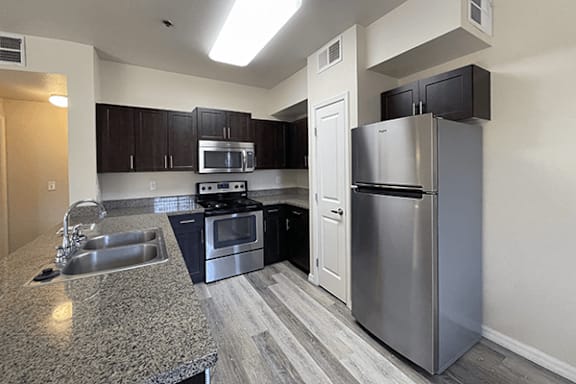 A kitchen with a granite counter top and stainless steel appliances.