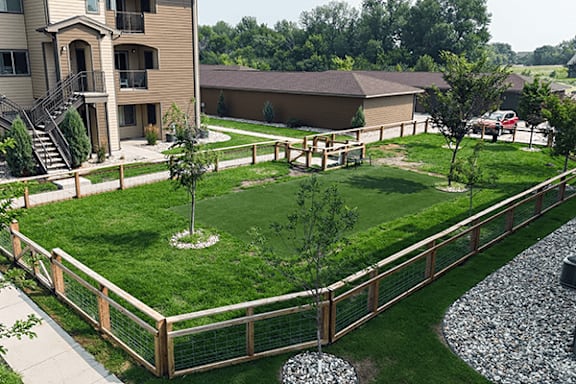 A backyard with a fence, a tree, and a gravel area.