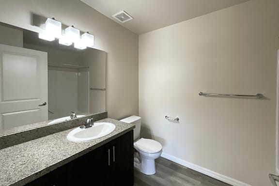 A bathroom with a sink, toilet, and mirror.
