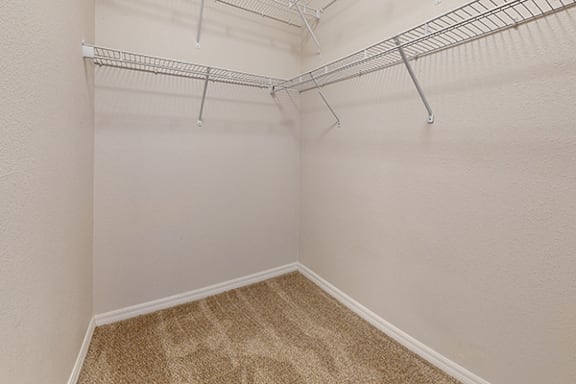 Empty room with a carpeted floor and metal racks on the wall.