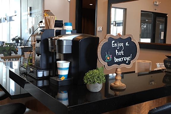 A sign on a counter that says "Enjoy a hot beverage!"