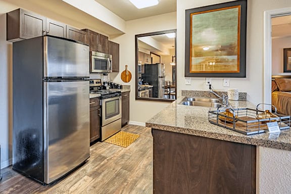 A kitchen with a stainless steel refrigerator and wooden cabinets.