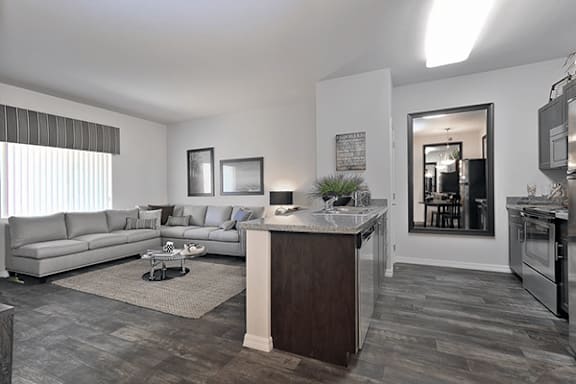 A modern living room with a grey sofa set and a wooden kitchen island.