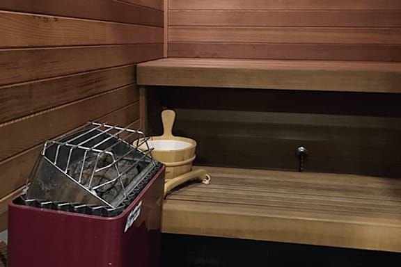 A wooden bench with a white container and a black grate on a red bin.