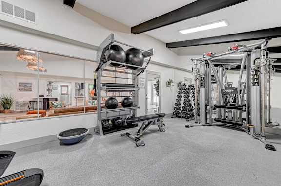 A gym with a variety of equipment including weights and a rowing machine.