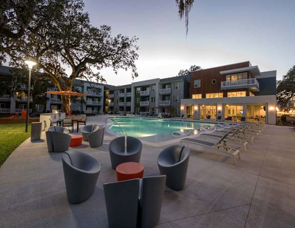 A modern outdoor pool area with lounge chairs and a building in the background.