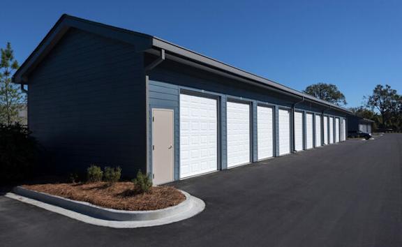 A long building with a grey roof and white garage doors.