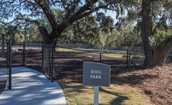 A sign that says Dog Park stands in front of a fence.